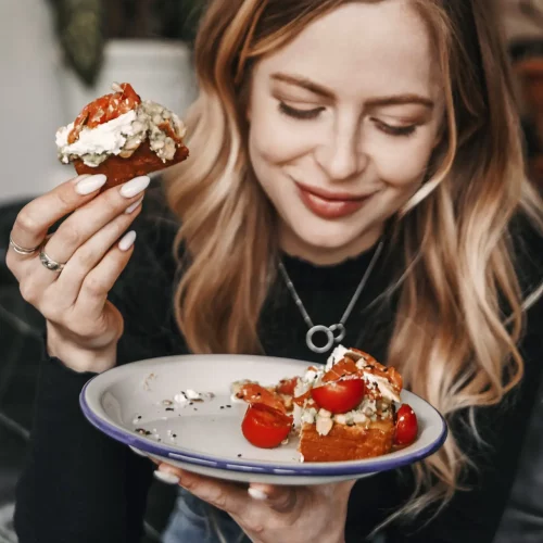 Young blonde woman is eating avocado toast for breakfast in a ca Young blonde woman is eating avocado toast for breakfast in a ca